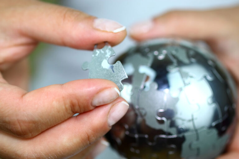 hand putting final piece in globe puzzle.